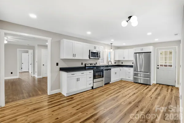 a kitchen with granite countertop a refrigerator cabinets and wooden floor