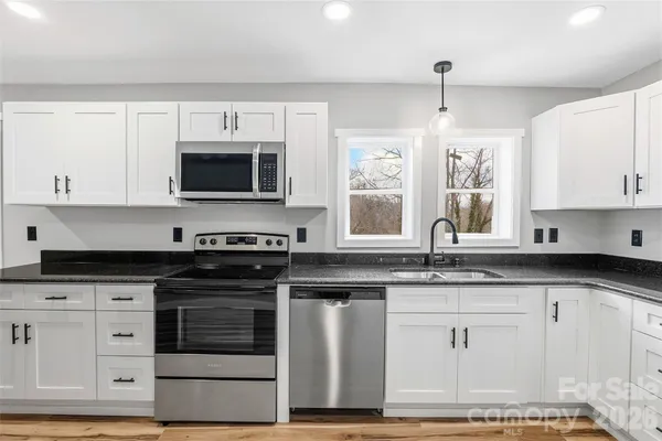 a kitchen with granite countertop a stove sink and microwave