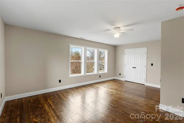 a view of an empty room with a window and wooden floor