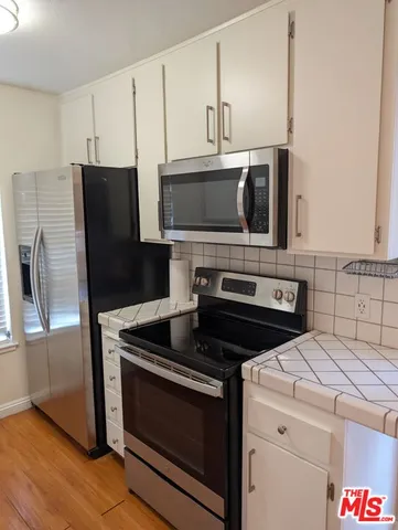 a kitchen with cabinets stainless steel appliances and wooden floor