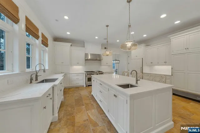 a large white kitchen with a large island oven a sink stainless steel appliances and cabinets