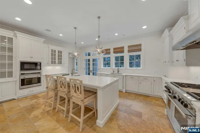 a kitchen with stainless steel appliances granite countertop a stove top oven a sink dishwasher a dining table and chairs with wooden floor