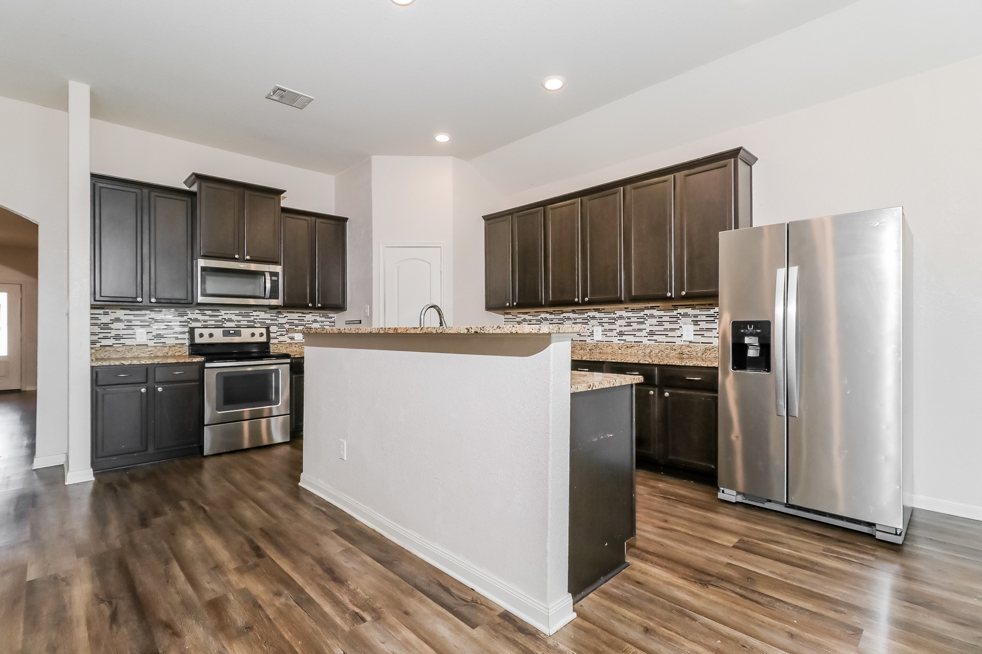 20017 Hubert R Humphrey Road Manor, TX 78653 - Photo 7 of 27 A well-appointed kitchen showcasing contemporary appliances and rich wood-toned flooring.