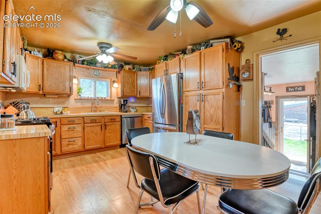 22558 Enoch Road Calhan, CO 80808 - Photo 32 of 50 a kitchen with stainless steel appliances a dining table chairs sink and wooden floor