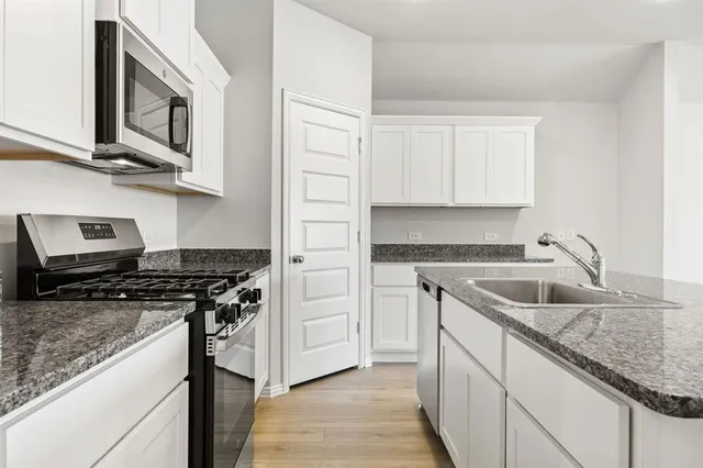 a kitchen with stainless steel appliances granite countertop a sink stove and cabinets