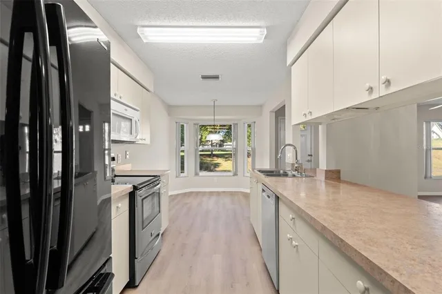 a large kitchen with granite countertop a large counter top space a sink stainless steel appliances and cabinets