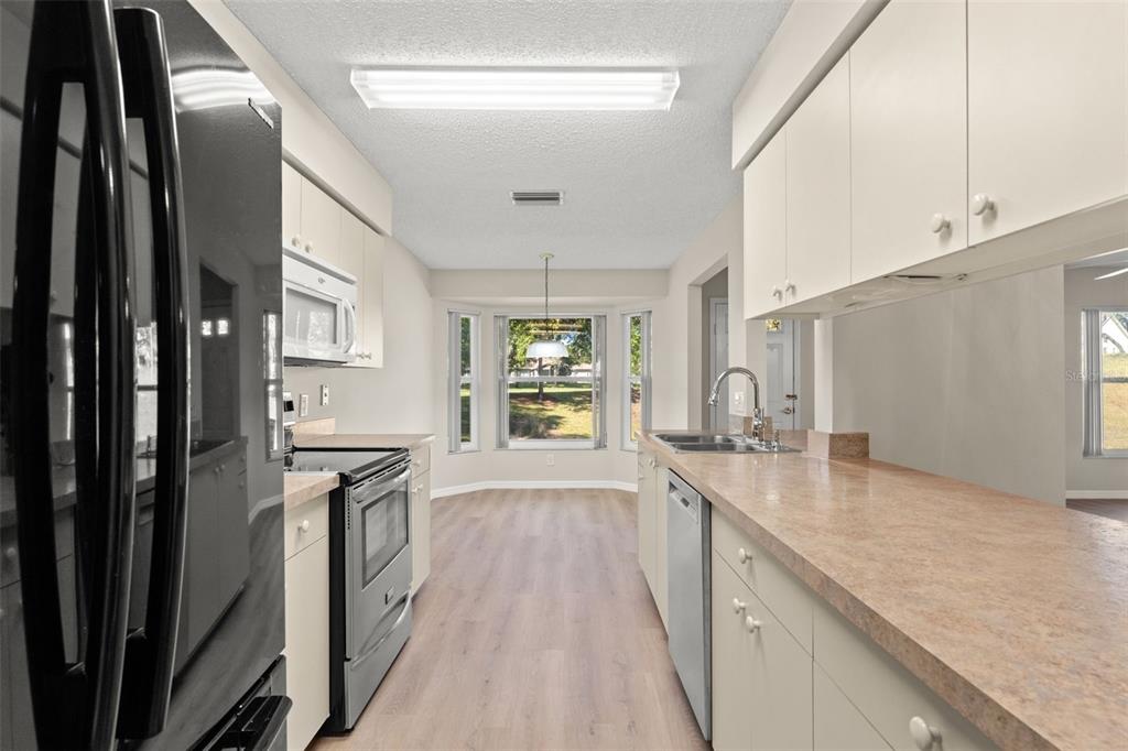 1415 Pinewood Hills Court Spring Hill, FL 34606 - Photo 18 of 45 a large kitchen with granite countertop a large counter top space a sink stainless steel appliances and cabinets