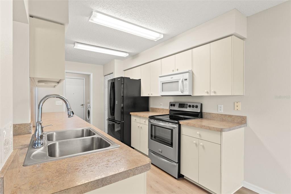1415 Pinewood Hills Court Spring Hill, FL 34606 - Photo 19 of 45 a kitchen with white cabinets a sink and stainless steel appliances