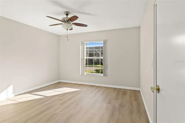 a view of empty room with wooden floor and fan