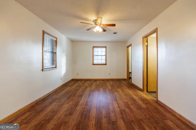 an empty room with wooden floor window and ceiling fan