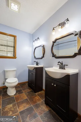 a bathroom with a double vanity sink mirror and toilet