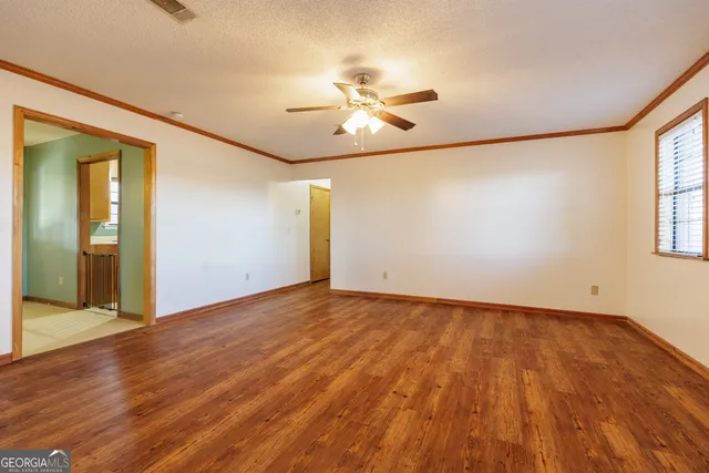 an empty room with wooden floor fan and windows