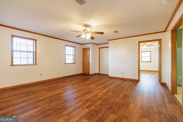 a view of an empty room with a window and wooden floor