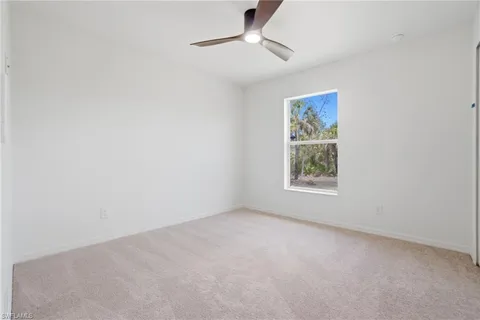 an empty room with a window and ceiling fan