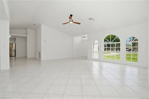 a view of an empty room with a window and kitchen view