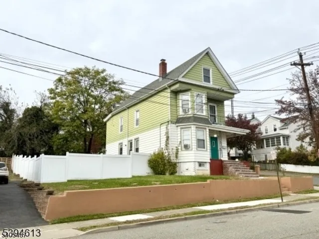 a view of a white house with a large windows and a yard with plants