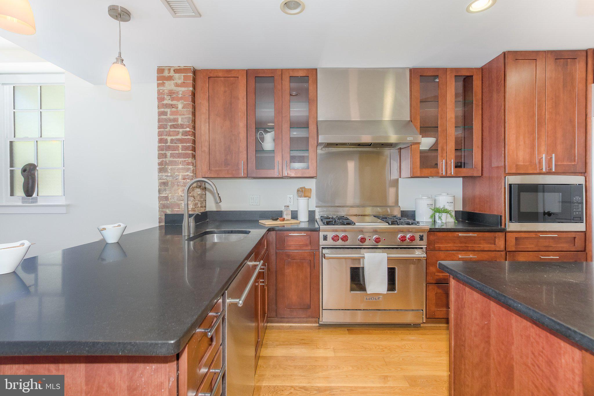 215 I Street Northeast, Unit 105 Washington, DC 20002 - Photo 16 of 41 a kitchen with kitchen island granite countertop a stove top oven a sink and dishwasher