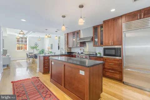 a kitchen with stainless steel appliances granite countertop a refrigerator a sink dishwasher a stove and a oven with wooden floor