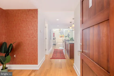 a view of a hallway with wooden floor and a bathroom