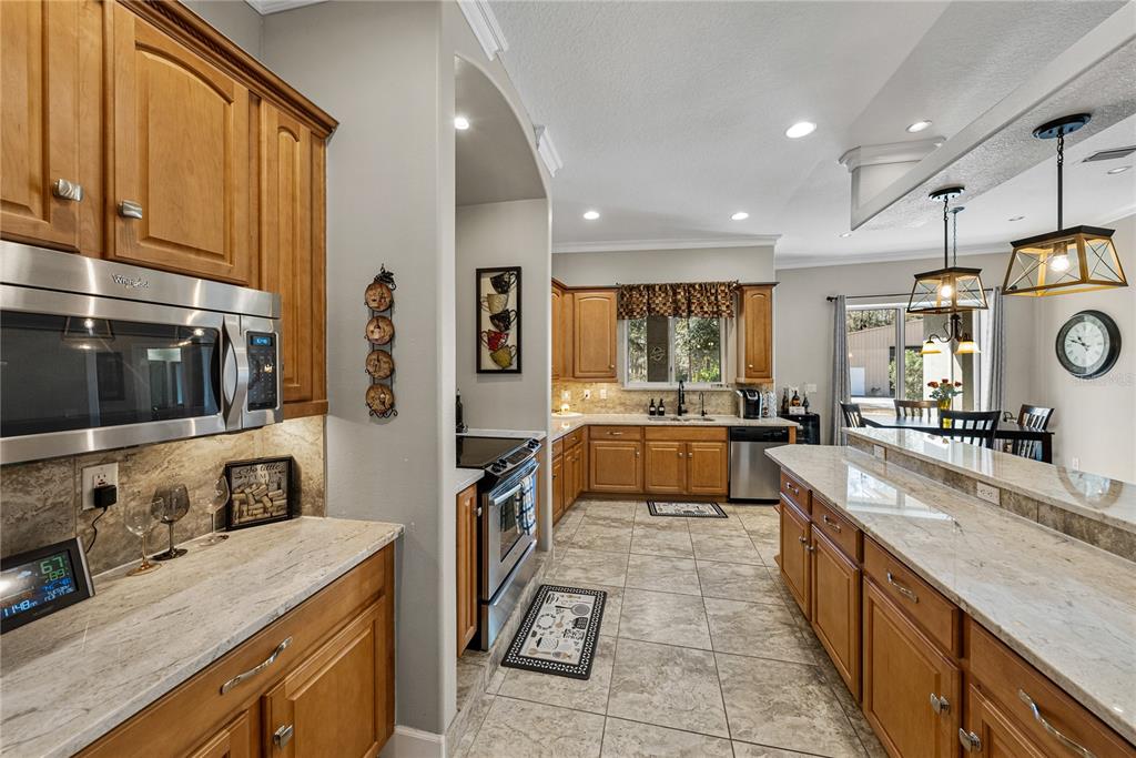27154 Raven Brook Road Wesley Chapel, FL 33544 - Photo 15 of 65 a large kitchen with stainless steel appliances granite countertop a large stove a sink dishwasher and cabinets with wooden floor