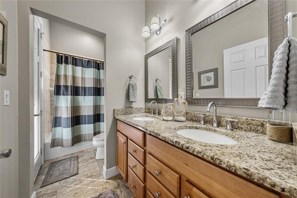 27154 Raven Brook Road Wesley Chapel, FL 33544 - Photo 39 of 65 a bathroom with a granite countertop sink a mirror a vanity and shower