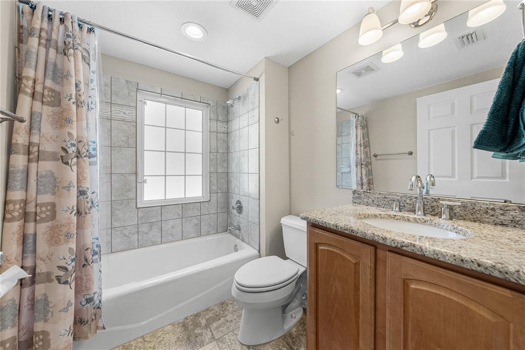 27154 Raven Brook Road Wesley Chapel, FL 33544 - Photo 47 of 65 a bathroom with a granite countertop sink a mirror a bathtub and a toilet