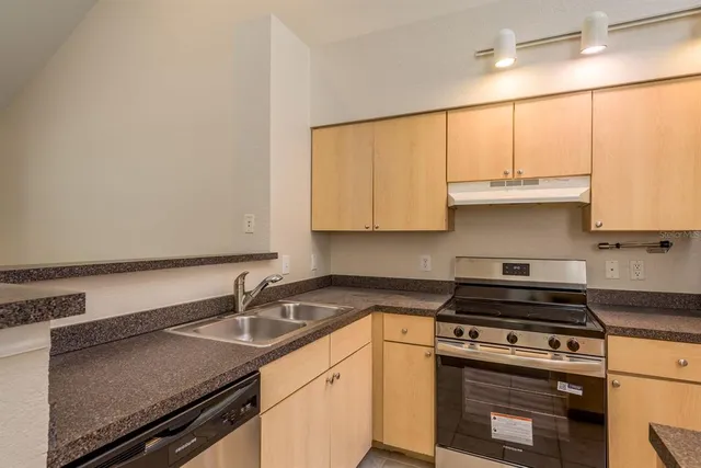 a kitchen with granite countertop a sink a stove and cabinets