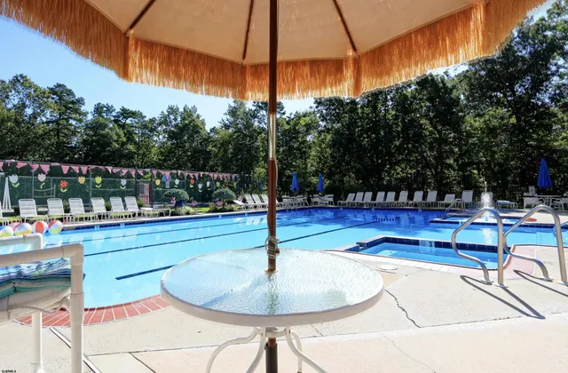 a swimming pool with a bench and trees in the background