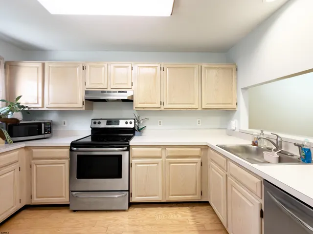 a kitchen with white cabinets appliances a sink and a window