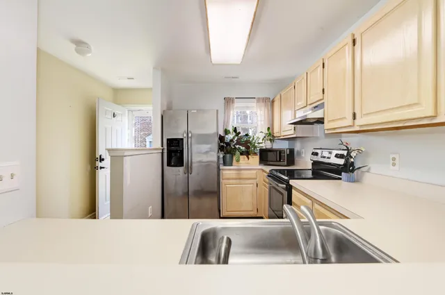 a kitchen with stainless steel appliances a refrigerator a sink a stove a microwave and cabinets