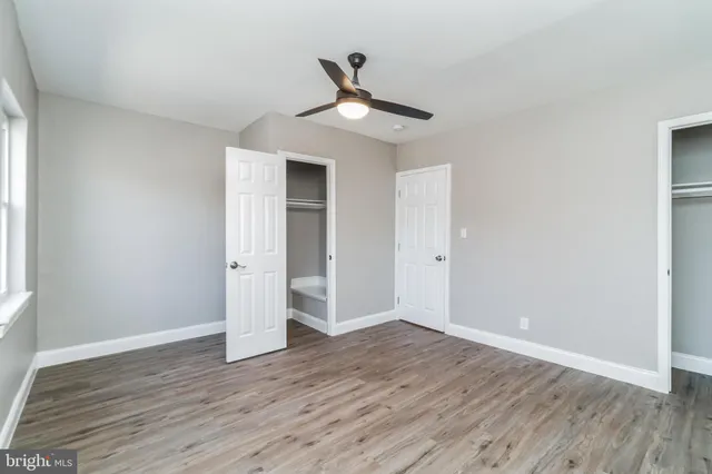 an empty room with wooden floor ceiling fan and windows