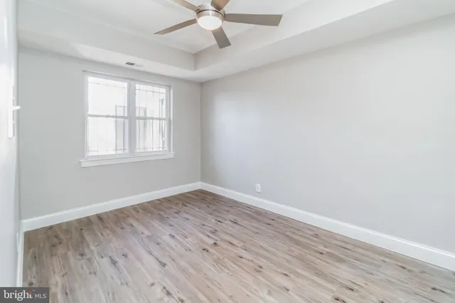 an empty room with wooden floor fan and windows