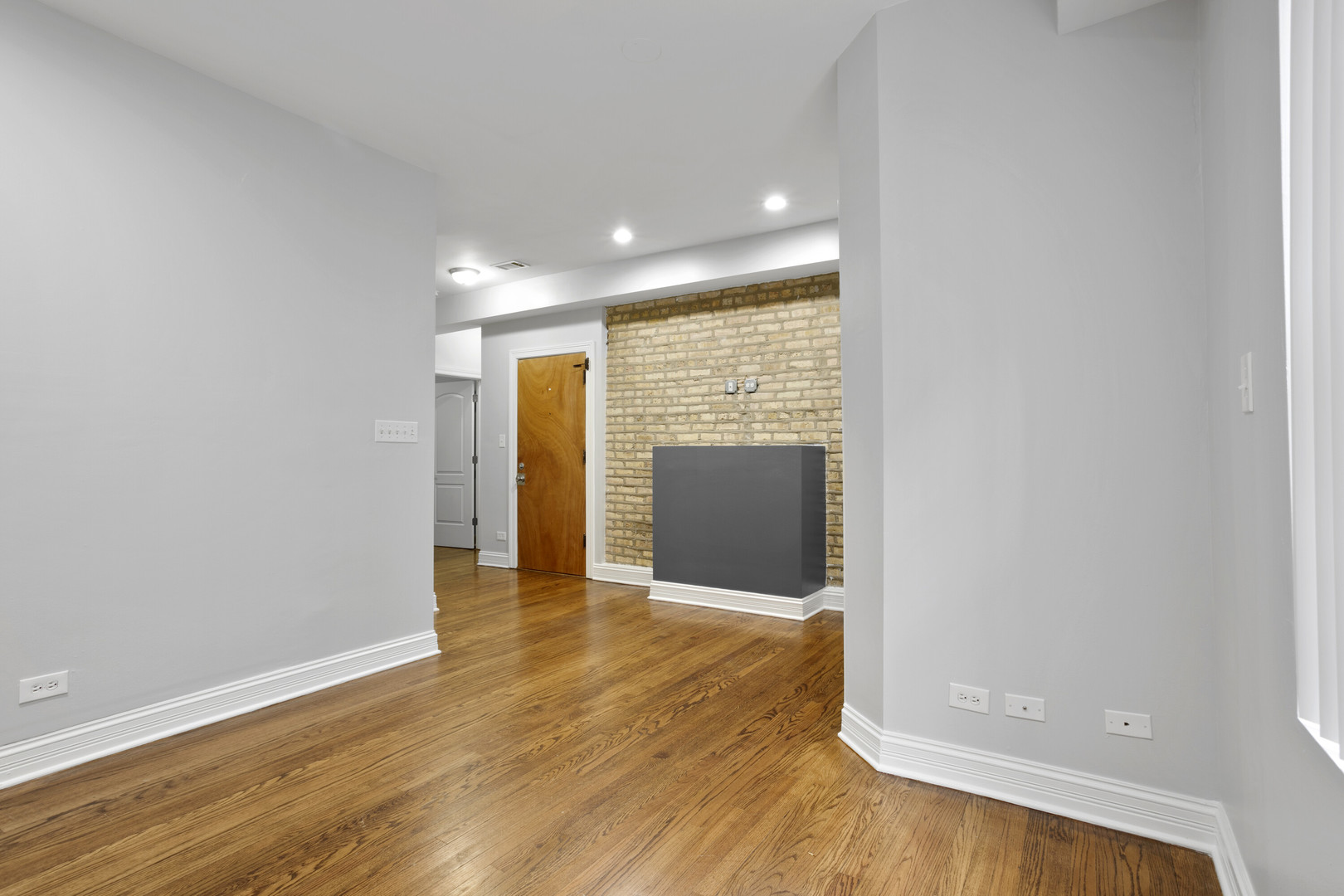 2005 West Jarvis Avenue, Unit 3 Chicago, IL 60645 - Photo 2 of 15 a view of an empty room with wooden floor and a window