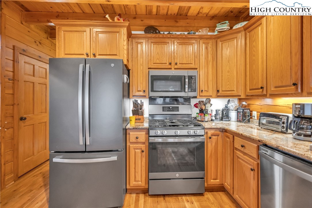 632 Big Tree Road West Jefferson, NC 28694 - Photo 18 of 48 a kitchen with stainless steel appliances granite countertop a refrigerator a stove and a sink with wooden cabinets