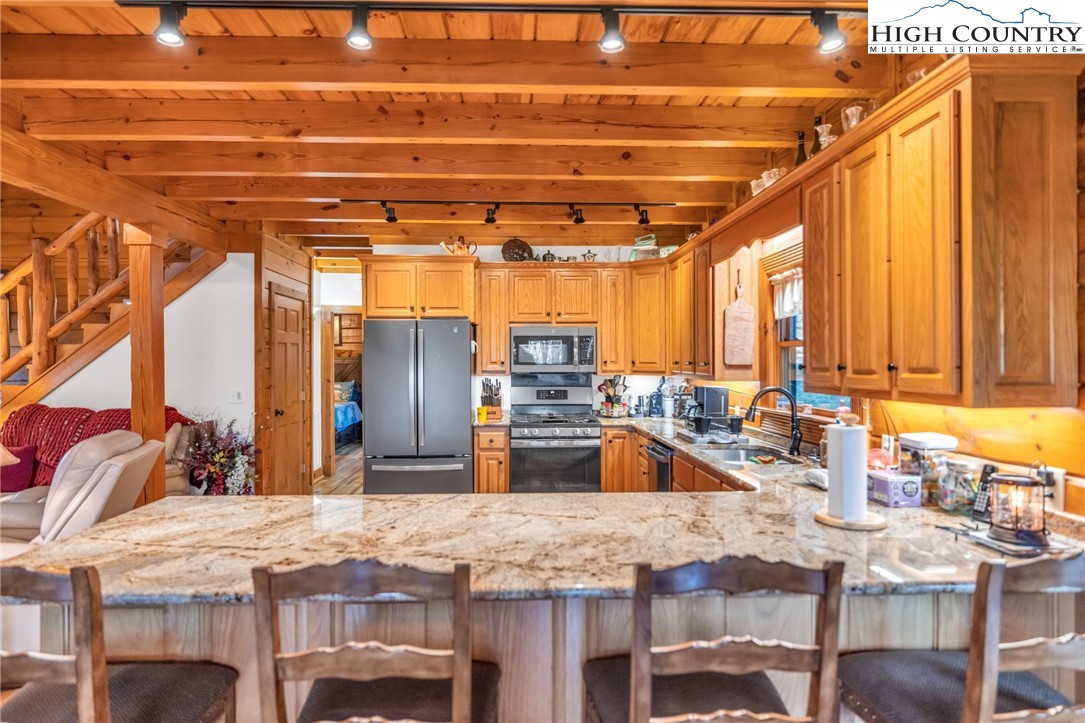632 Big Tree Road West Jefferson, NC 28694 - Photo 20 of 48 a kitchen with a stove a sink and a dining table with wooden cabinet