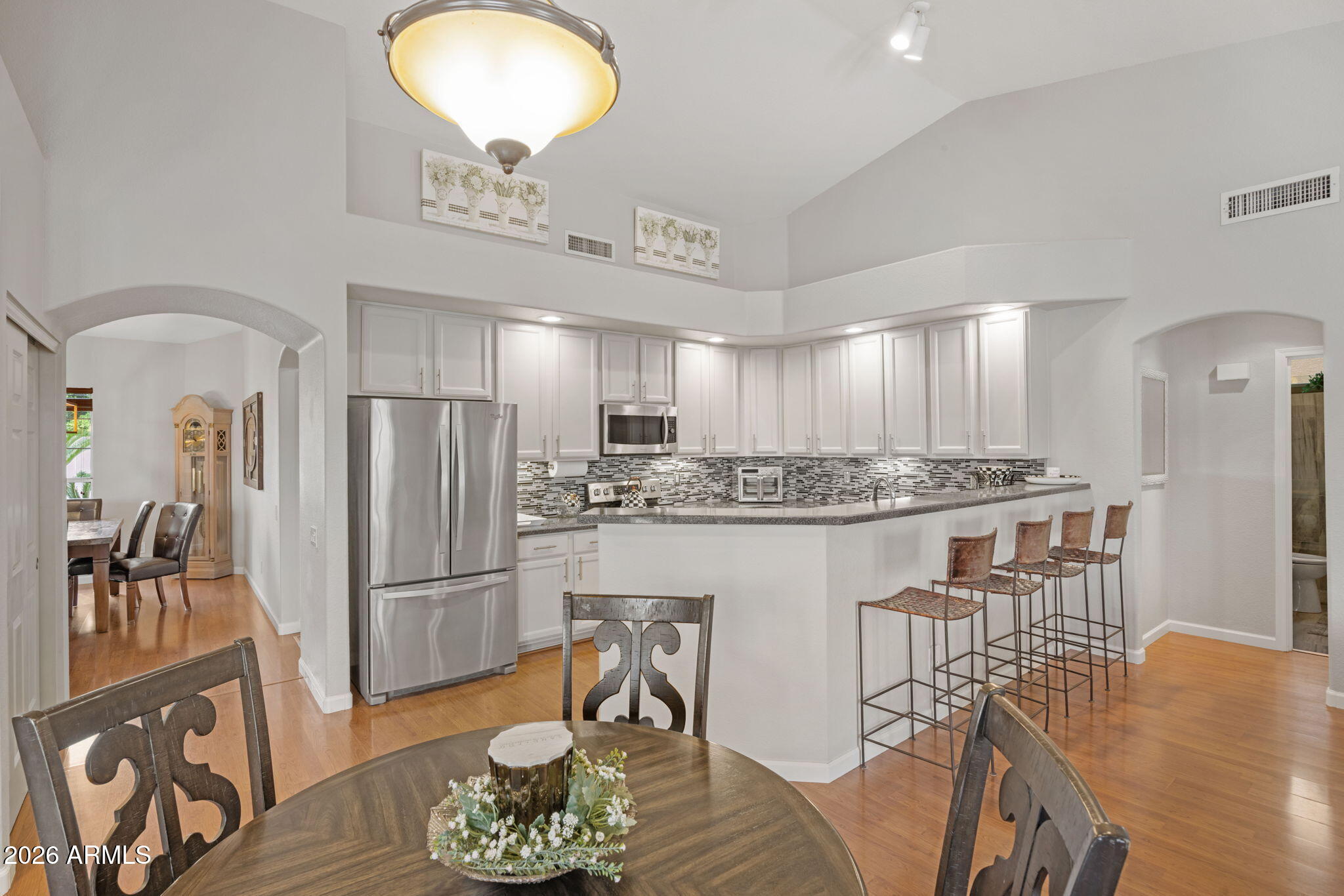 16008 South 38th Way Phoenix, AZ 85048 - Photo 10 of 47 a kitchen with stainless steel appliances granite countertop a refrigerator a stove a microwave oven a dining table and chairs with wooden floor