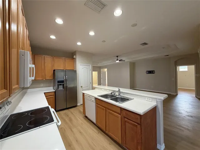 an empty room with wooden floor cabinet and windows