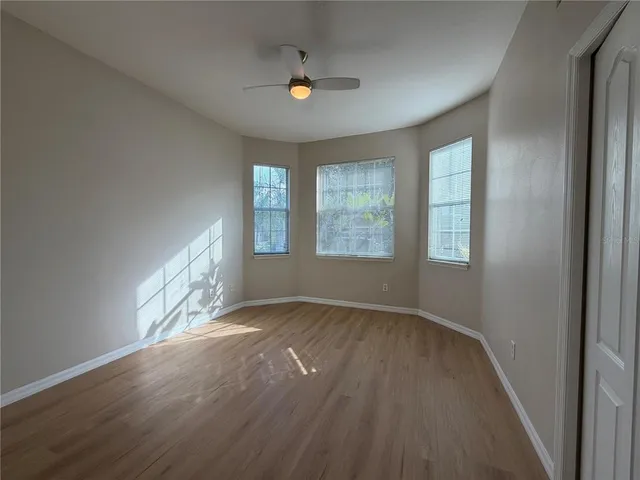 an empty room with wooden floor and windows