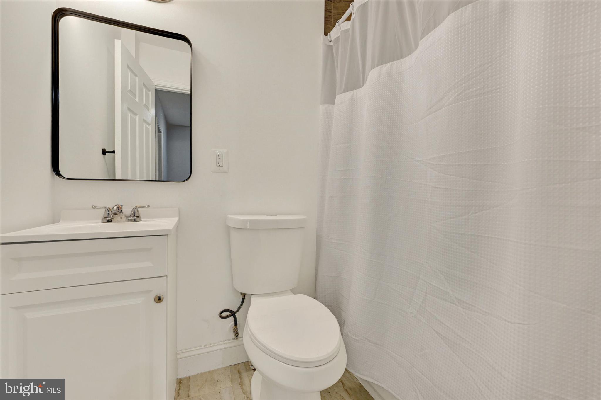 3105 Frisby Street Baltimore, MD 21218 - Photo 16 of 22 a bathroom with a toilet sink vanity and mirror