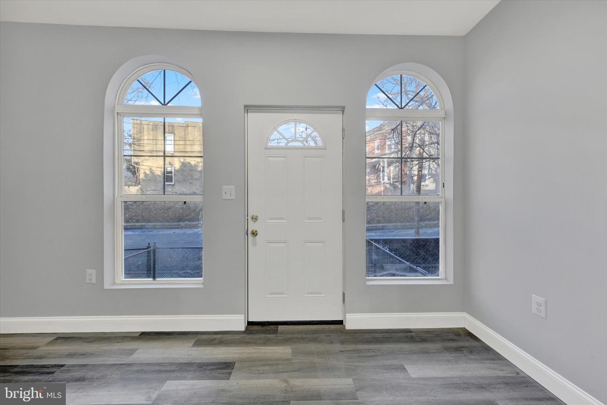 3105 Frisby Street Baltimore, MD 21218 - Photo 2 of 22 an empty room with wooden floor a ceiling fan and windows