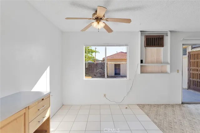 a view of an empty room with window and chandelier fan