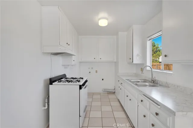 a kitchen with granite countertop a sink a stove and cabinets