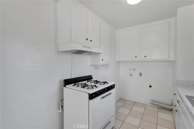 a kitchen with granite countertop white cabinets stove and sink