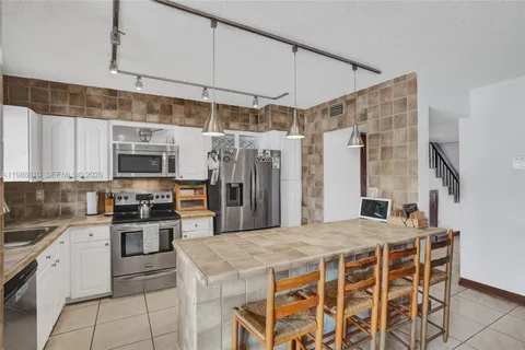 a kitchen with stainless steel appliances kitchen island granite countertop a table chairs microwave and refrigerator