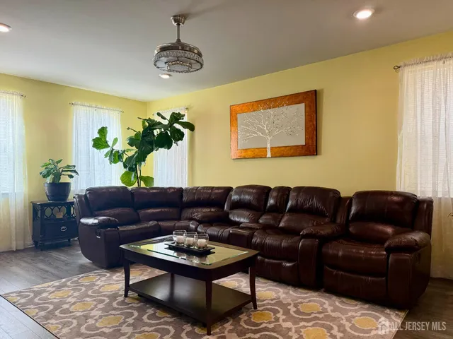a living room with furniture and a dining table with wooden floor