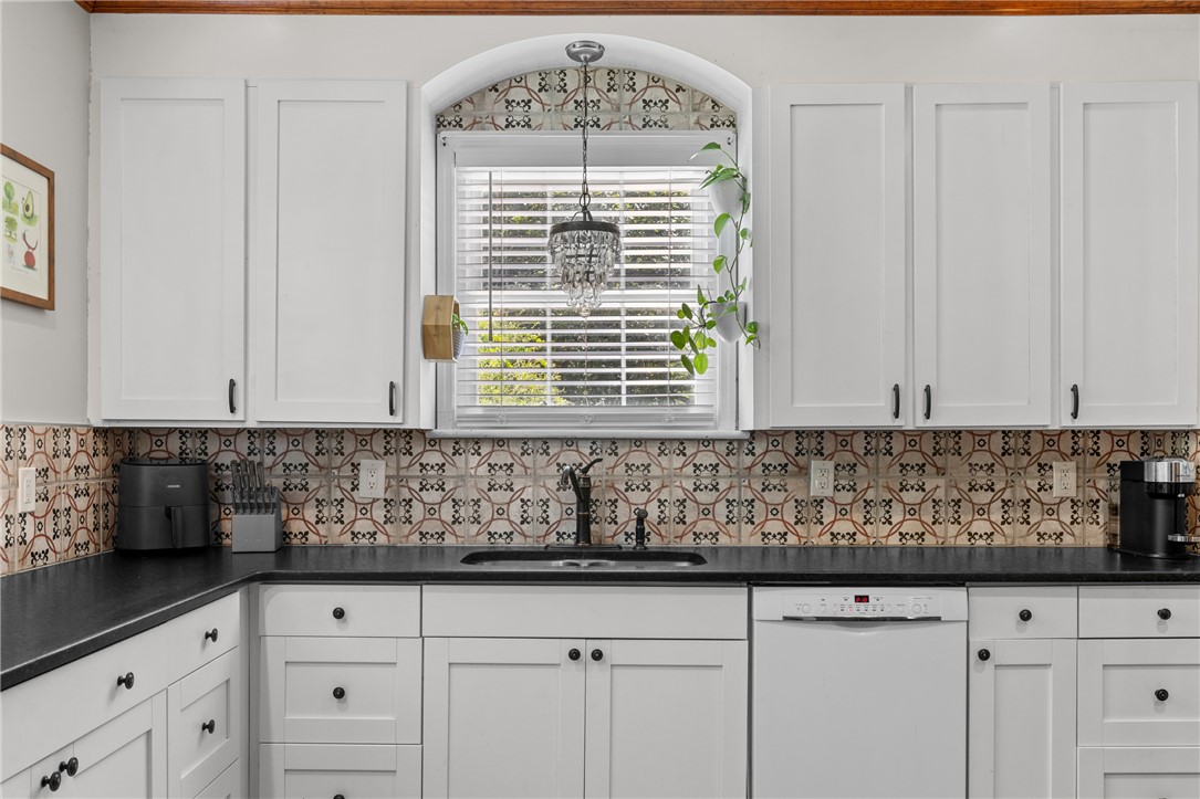 704 Cherry Street Pendleton, SC 29670 - Photo 11 of 28 White cabinetry, a deep sink, and unique backsplash tiles create a clean, functional kitchen space.
