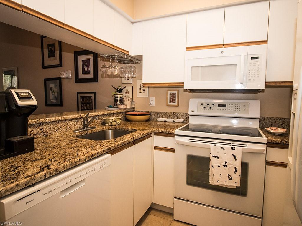 3321 Olympic Drive, Unit 623 Naples, FL 34105 - Photo 8 of 20 a kitchen with stainless steel appliances granite countertop a stove a sink and a microwave