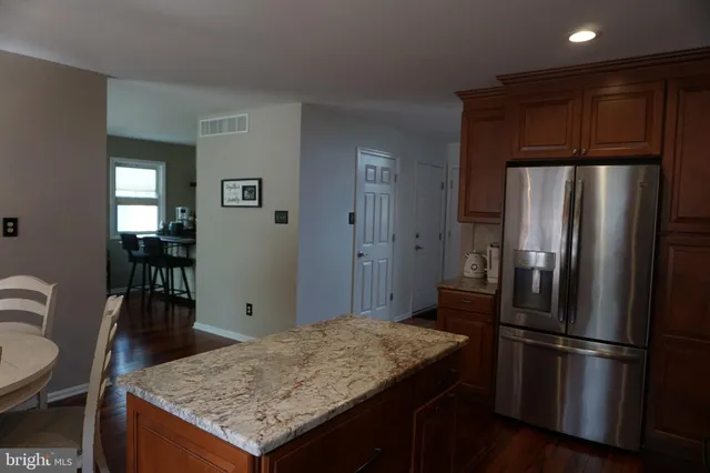 a kitchen with stainless steel appliances granite countertop a refrigerator a stove and a sink with wooden floor