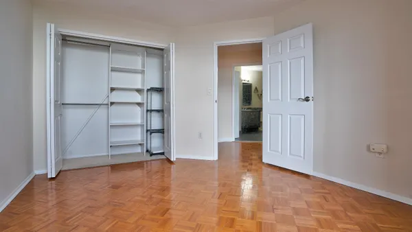 a view of an empty room with wooden floor and closet