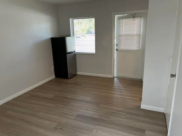 an empty room with wooden floor cabinet and mirror